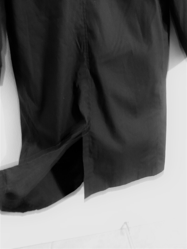 May include: A black long-sleeved shirt with a single slit in the back.