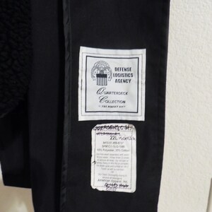 May include: Black jacket with a white label that reads "Defense Logistics Agency Quarterdeck Collection The Perfect Fit". The label also has a seal with the words "United States of America".