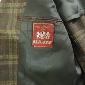 May include: A brown and green plaid jacket with a red label that reads "Made Expressly For Durkin & Durkin".