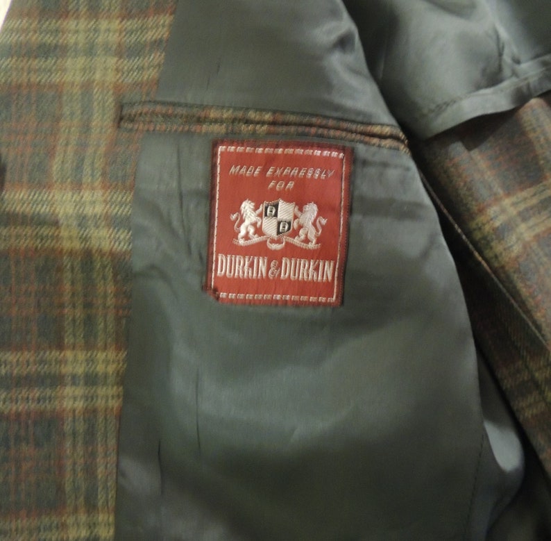 May include: A brown and green plaid jacket with a red label that reads "Made Expressly For Durkin & Durkin".