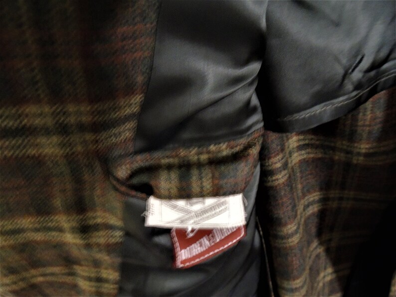 May include: A brown, green, and red plaid jacket with a black satin lining. The jacket has a label that reads "Made in England" and "Dunlop & Dunlop".