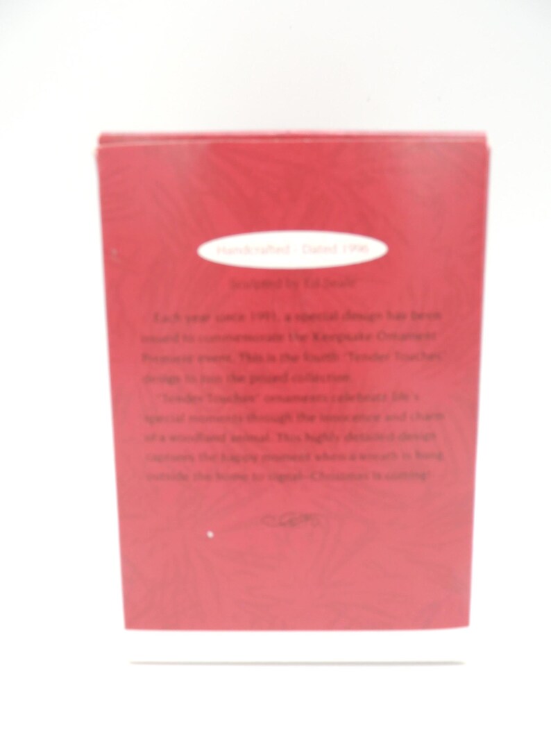 Może przedstawiać: Czerwone pudełko z białym tekstem i białą owalną etykietą. Tekst na pudełku zawiera słowa "Handcrafted - Dated 1996" i "Tender Touches". Pudełko znajduje się na białym tle.