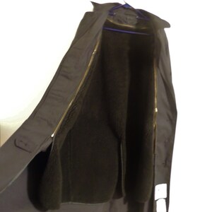 May include: A black long coat with a zipper closure and a fleece lining. The coat is hanging on a hanger.
