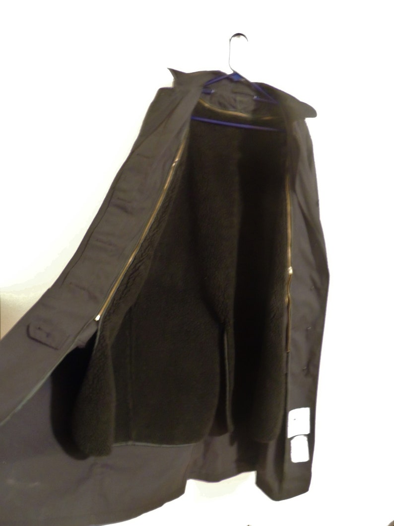 May include: A black long coat with a zipper closure and a fleece lining. The coat is hanging on a hanger.
