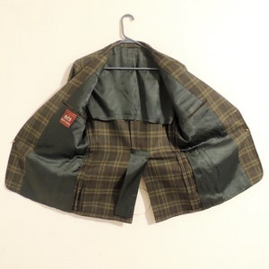 May include: A brown and green plaid blazer with a black lining. The blazer has a label that says "Made in Italy".
