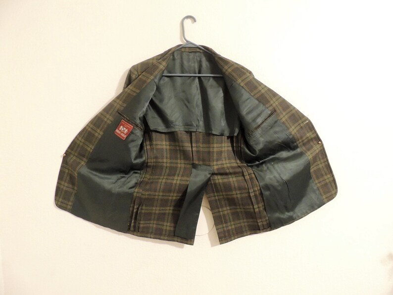 May include: A brown and green plaid blazer with a black lining. The blazer has a label that says "Made in Italy".