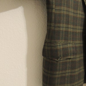 May include: A brown and green plaid blazer with a single button closure and a pocket on the left side.