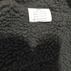 May include: A black fabric label with white text that reads "220 BAIS 01 AA SIST SPMIC 1.150 150 Acrylic DRY CLEAN ONLY DO NOT PRESS".