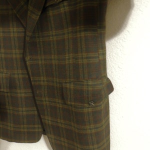 May include: A brown and green plaid blazer with two flap pockets and a button closure.