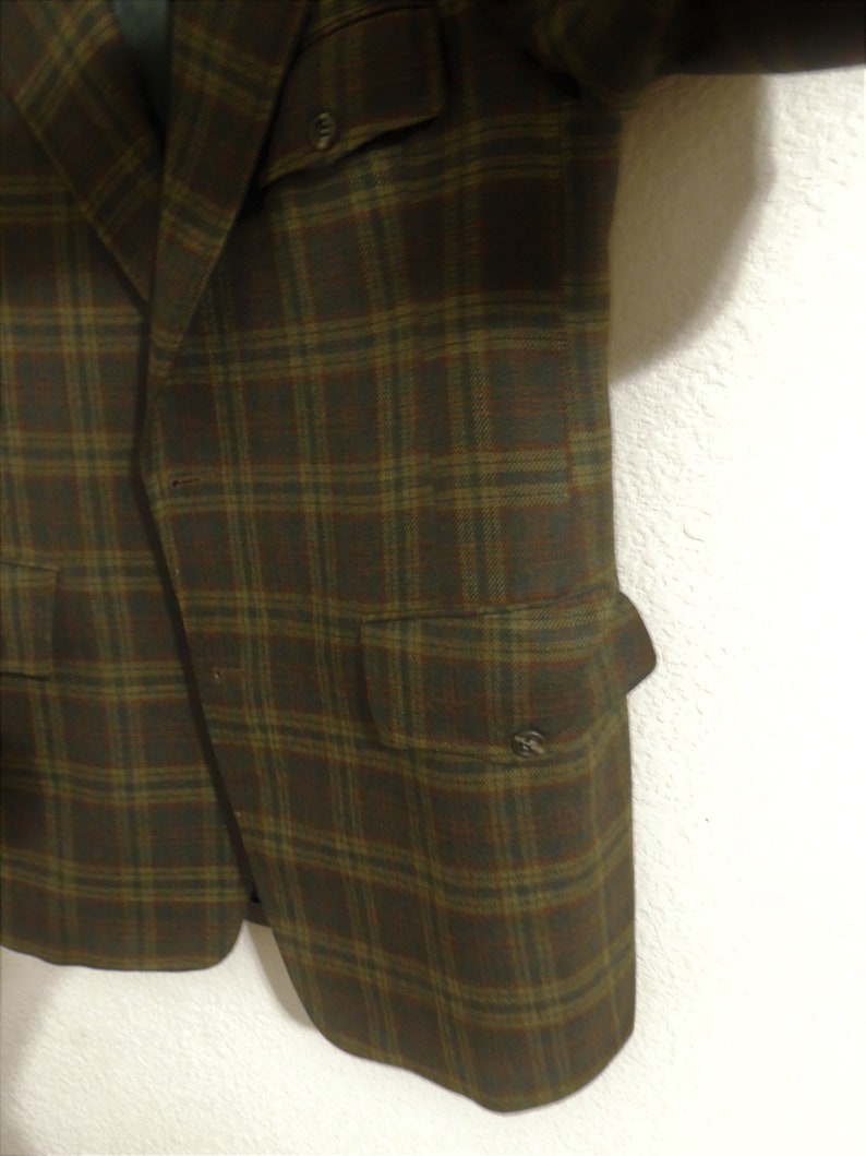 May include: A brown and green plaid blazer with two flap pockets and a button closure.