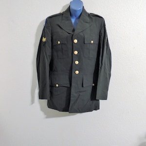 May include: A dark green military uniform jacket with gold buttons and a patch on the left sleeve.