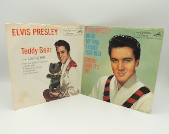 May include: A vintage 45 RPM record single by Elvis Presley. The front cover features a color photo of Elvis Presley wearing a white sweater with black and red stripes. The back cover features a color photo of Elvis Presley holding a teddy bear. The title of the record is "Teddy Bear" and the B-side is "Loving You".