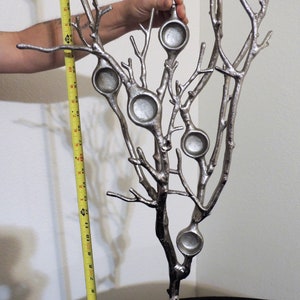 Puede incluir: Escultura de &aacute;rbol de metal plateado con seis candelabros circulares. La escultura mide aproximadamente 30 cm de altura. Las ramas del &aacute;rbol se extienden hacia arriba y hacia afuera, creando una pieza decorativa &uacute;nica.
