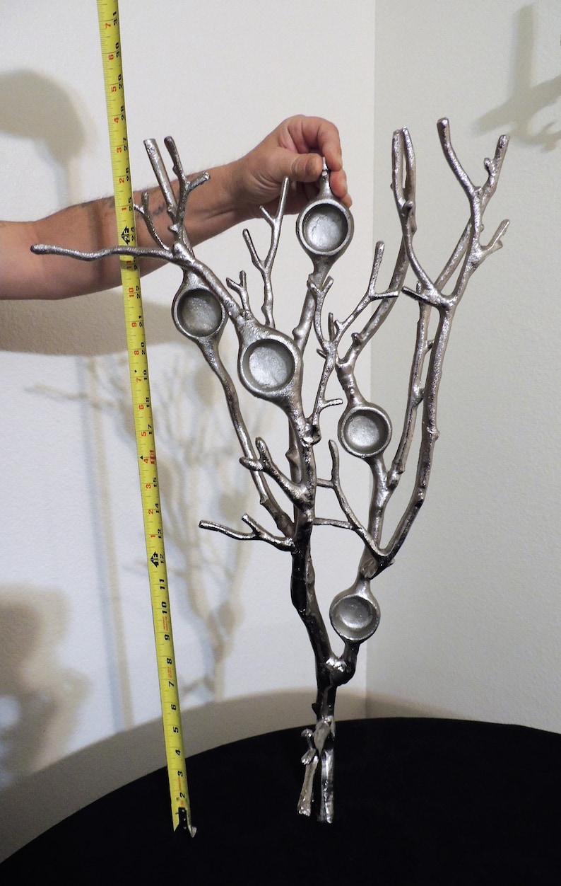 Puede incluir: Escultura de &aacute;rbol de metal plateado con seis candelabros circulares. La escultura mide aproximadamente 30 cm de altura. Las ramas del &aacute;rbol se extienden hacia arriba y hacia afuera, creando una pieza decorativa &uacute;nica.