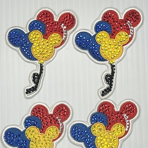 May include: Four iron-on patches featuring Mickey Mouse ears shaped balloons in red, yellow, and blue with rhinestones.