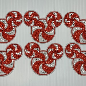 May include: Six red and white candy cane Mickey Mouse shaped iron-on patches with rhinestones.