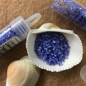 May include: A small container of light purple seed beads, size 11/0, in a seashell. The container has a barcode and the text "DP-B00-0240".
