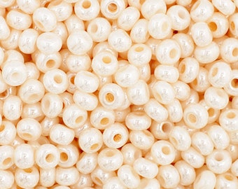 May include: A close-up image of a pile of small, round, white beads with a pearlescent finish. The beads are uniform in size and shape, and they have a smooth, glossy surface.