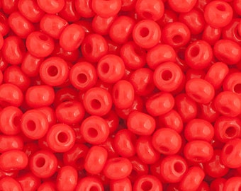 May include: A close-up view of a large quantity of small, round, red seed beads. The beads are all the same size and shape, and they are arranged in a random pattern.