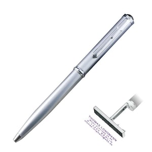 Op de afbeelding: Een zilveren pen met een clip en een zwarte punt. De pen staat schuin over de afbeelding. Een kleine stempel met de tekst "THOMAS LONGMANN" staat in de rechter benedenhoek.