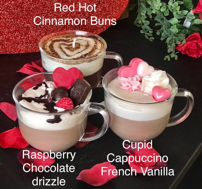May include: Three glass mugs filled with different flavored hot chocolate. The mugs are labeled "Raspberry Chocolate drizzle", "Cupid Cappuccino French Vanilla", and "Red Hot Cinnamon Buns".