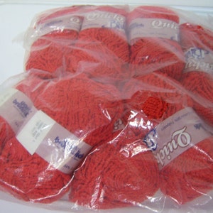 May include: A package of red yarn skeins. The yarn is in clear plastic packaging. Each skein has a label that reads "Quick" and "Brunswick". The yarn appears to be a medium weight, suitable for knitting or crocheting projects.