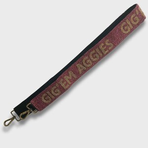 May include: A maroon and gold beaded strap with the words "GIG'EM AGGIES" in gold lettering. The strap has a black backing and gold-colored metal clasps.