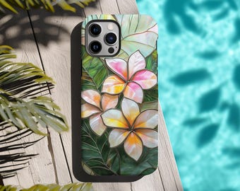 May include: A phone case featuring a floral design with white, yellow, and pink plumeria flowers. The case has a green background with leaves and a black border. The phone case is on a wooden surface.