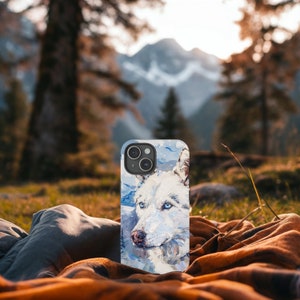 May include: A white wolf phone case with a blue and white painted background. The case has a camera cutout and a white wolf with blue eyes.