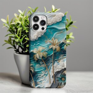 May include: A phone case with a tropical beach scene. The case features a blue and green ocean with white waves, gold accents, and palm trees. The camera lens is visible on the back of the case.