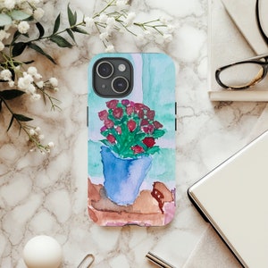 May include: A phone case with a watercolor painting of a potted plant with pink flowers. The background is a light blue and green watercolor wash.