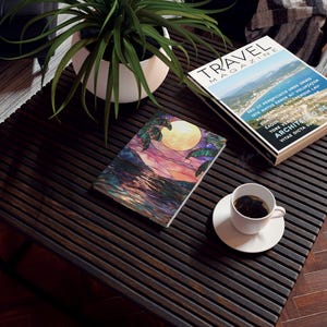 Peut inclure: Une illustration colorée de style vitrail représentant une scène de plage tropicale avec des palmiers, une pleine lune et un coucher de soleil sur l'océan. L'illustration est imprimée sur un carnet.