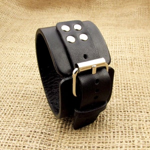 May include: Black leather cuff bracelet with a silver buckle and four silver studs.