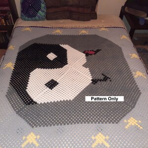 May include: A crocheted blanket with a gray and white yin yang symbol in the center. The blanket has a gray background with yellow stars around the edges. The text "Pattern Only" is printed on the blanket.