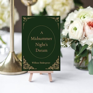 May include: A green card with gold lettering on a wooden easel. The card reads "A Midsummer Night's Dream" by William Shakespeare.