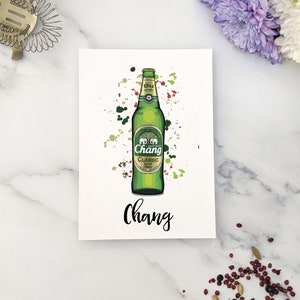 Op de afbeelding: Een groene bierfles met een wit etiket waarop "Chang Classic Beer" en twee olifanten staan. De fles is omgeven door kleurrijke verfspatten. Het woord "Chang" staat in zwart onder de fles.
