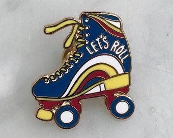 Könnte beinhalten: Eine goldfarbene Emaille-Anstecknadel mit einem blauen, roten, gelben und weißen Rollschuh mit dem Text "Let's Roll" an der Seite.