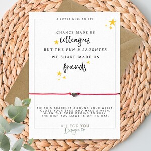 May include: A greeting card with a red string bracelet. The card has text that reads "Chance made us colleagues, but the fun & laughter we share made us friends." The card is on a woven background.