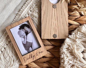 May include: Wooden photo frame with a black and white photo of a father and child. The frame has the text "Daddy & me" engraved on the bottom.