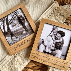 May include: Two wooden photo frames with engraved messages. The first frame shows a father and son playing football and says "football buddies!" The second frame shows a father and daughter hugging and says "To the world you are a dad, but to us you are the world."