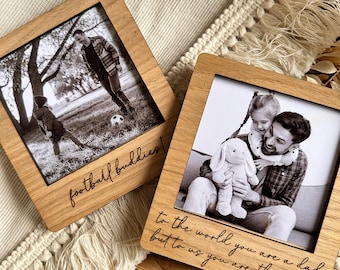 May include: Two wooden photo frames with engraved messages. The first frame shows a father and son playing football and says "football buddies!" The second frame shows a father and daughter hugging and says "To the world you are a dad, but to us you are the world."