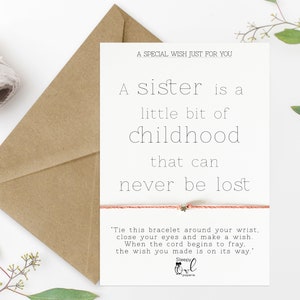 May include: A white card with a pink and gold bracelet on it. The card reads "A sister is a little bit of childhood that can never be lost."  The card also includes instructions for making a wish with the bracelet.