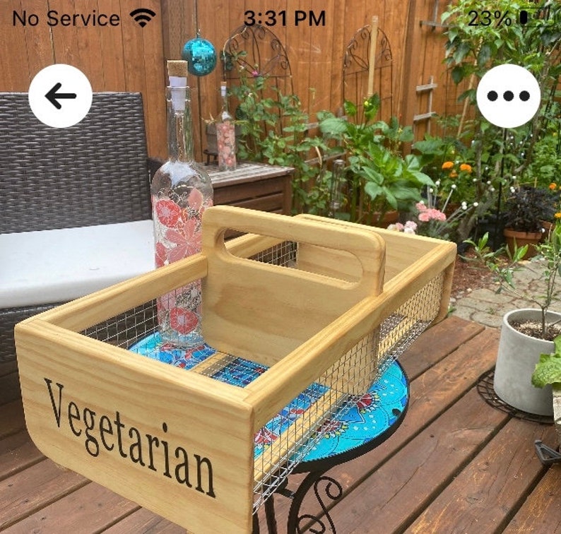 Op de afbeelding: Een houten dienblad met een draadgaas inzet en een handvat. Het dienblad is gelabeld "Vegetarisch" en staat op een blauw-wit betegelde ondergrond.