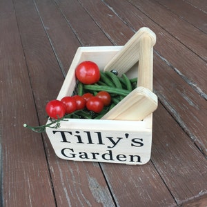 May include: A wooden crate with a handle, labeled "Tilly's Garden", filled with green beans and red tomatoes.