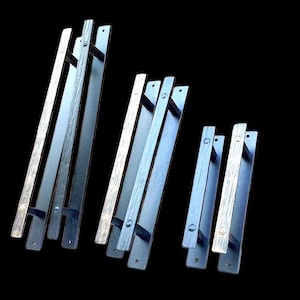 May include: Four black metal door handles with a wood grain finish. The handles are different sizes and are arranged in a row from largest to smallest.