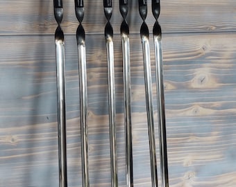 May include: Six black-handled metal skewers with twisted metal shafts. The skewers are arranged vertically against a light wood background.