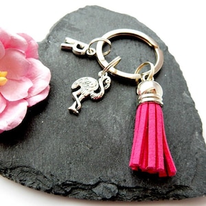 May include: Pink flamingo keychain with a pink tassel charm. The keychain is attached to a silver ring.