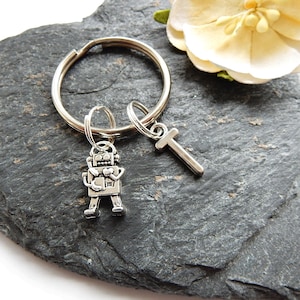 May include: Silver robot keychain with a heart and the letter T charm attached to a silver key ring.