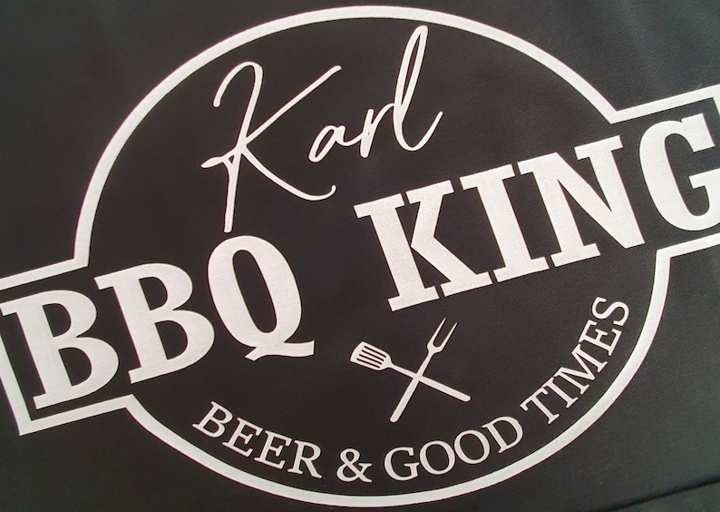Pu&ograve; includere: Sfondo nero con un logo circolare bianco che recita "Karl BBQ KING" in un font stilizzato. Il logo include una forchetta e una spatola incrociate e le parole "BEER & GOOD TIMES".