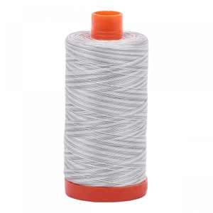 May include: A spool of white thread with gray stripes, wound around a plastic bobbin with an orange top and bottom.